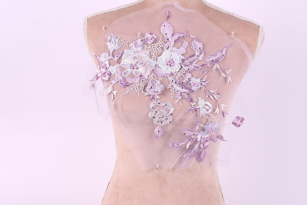 A mannequin with a delicate, floral-patterned fabric draped over its back.