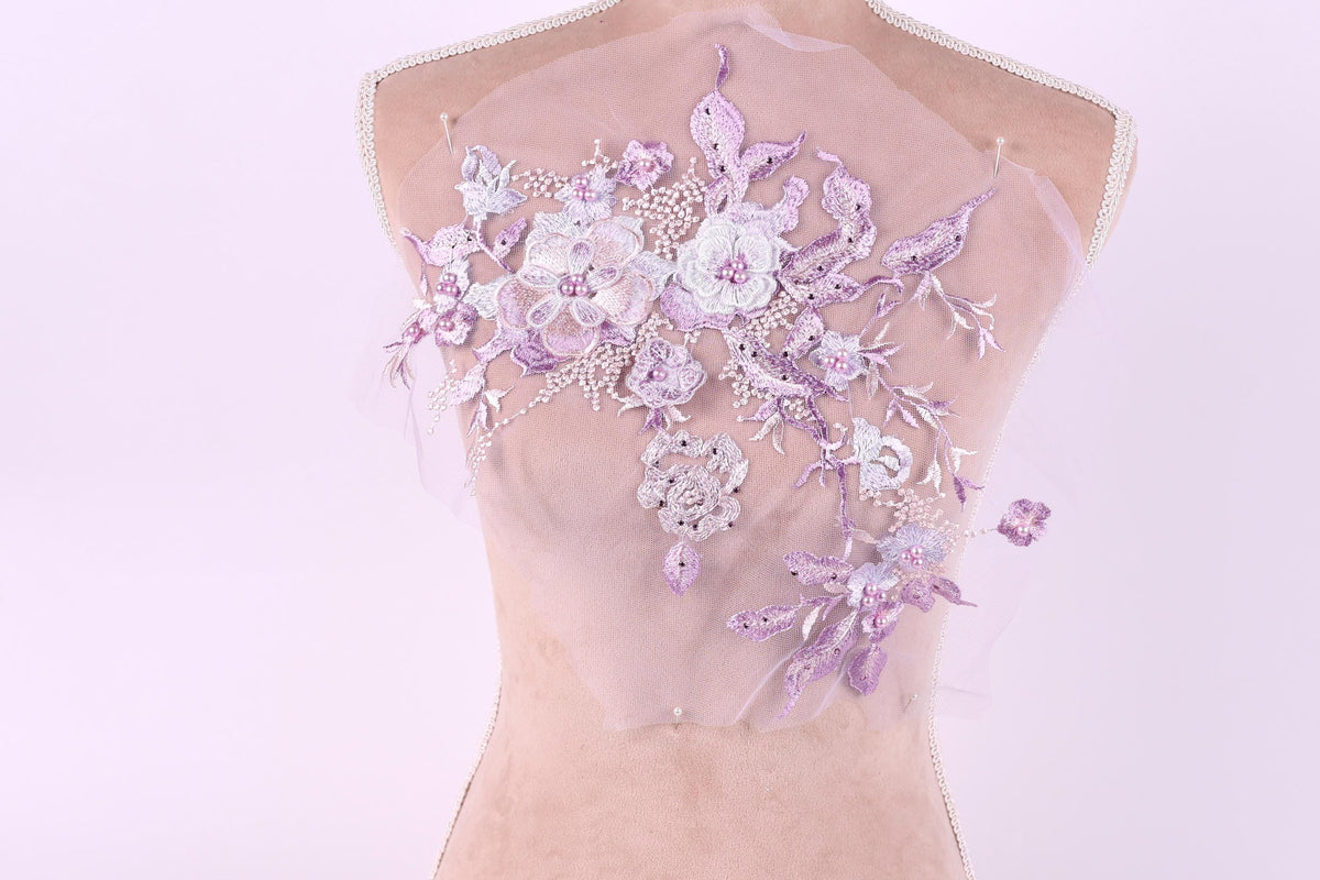 A mannequin with a delicate, floral-patterned fabric draped over its back.