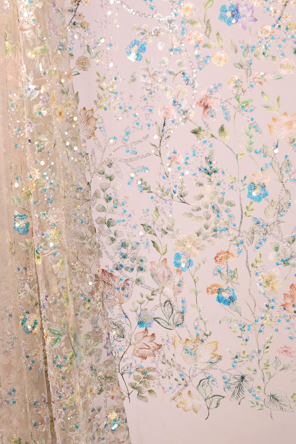 a close-up view of a delicate, intricately embroidered fabric with a floral pattern. The fabric is adorned with a variety of colorful flowers and leaves, creating a visually appealing and detailed design. The image showcases the craftsmanship and artistry involved in creating such a piece of textile art.