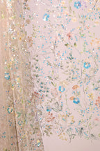 a close-up view of a delicate, intricately embroidered fabric with a floral pattern. The fabric is adorned with a variety of colorful flowers and leaves, creating a visually appealing and detailed design. The image showcases the craftsmanship and artistry involved in creating such a piece of textile art.