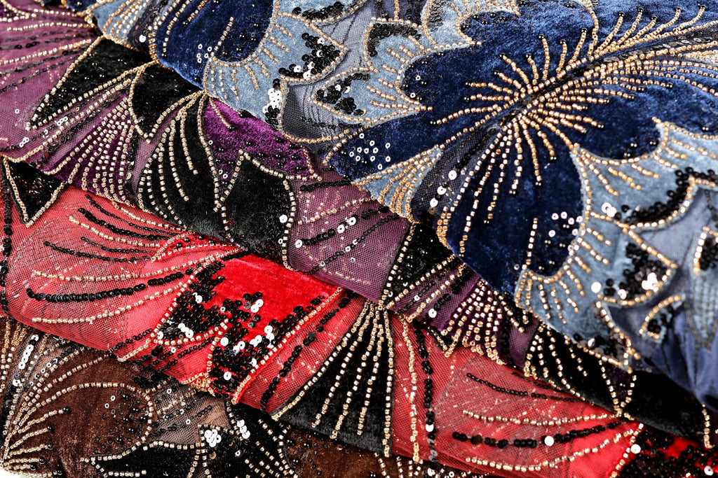 The image is a close-up of a fabric with a vibrant, colorful floral pattern. The fabric is adorned with numerous small beads and sequins, creating a visually striking and intricate design.