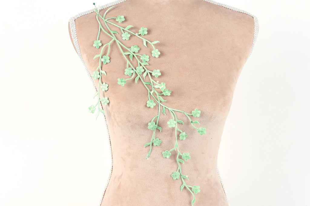 a mannequin torso with a delicate green floral embroidery on the back.