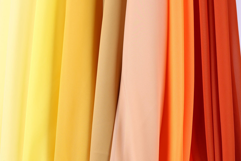 A close-up view of a collection of fabric swatches in various colors, including yellow, orange, and red.