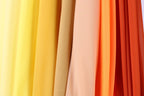 A close-up view of a collection of fabric swatches in various colors, including yellow, orange, and red.