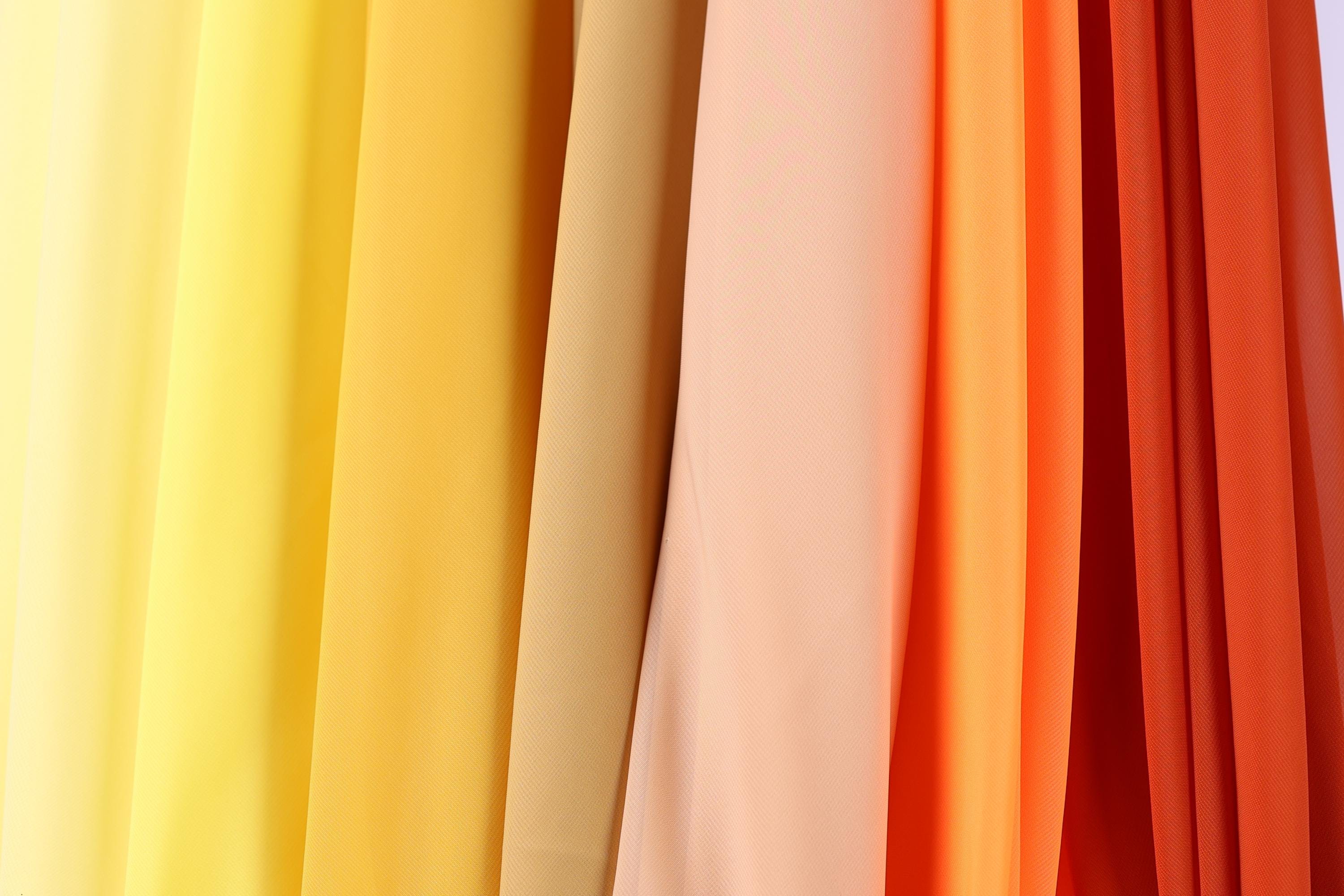 A close-up view of a collection of fabric swatches in various colors, including yellow, orange, and red.