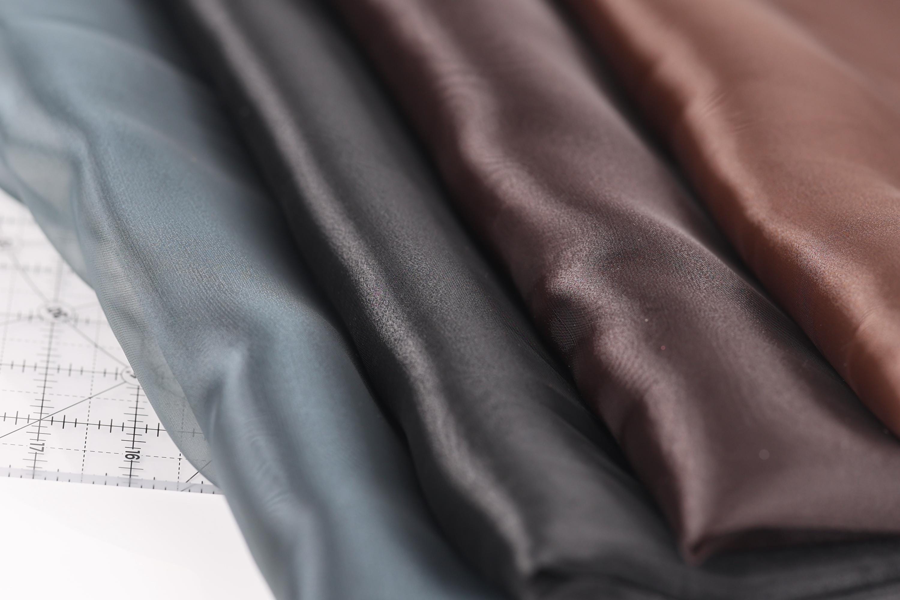 a close-up view of several fabric swatches, including a dark brown fabric, a light blue fabric, and a dark gray fabric.
