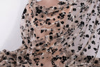 a close-up view of a sheer fabric with a floral pattern. The fabric appears to be made of sheer material, with a black and white floral design covering the entire surface. The fabric is draped over a surface, creating a draped effect.