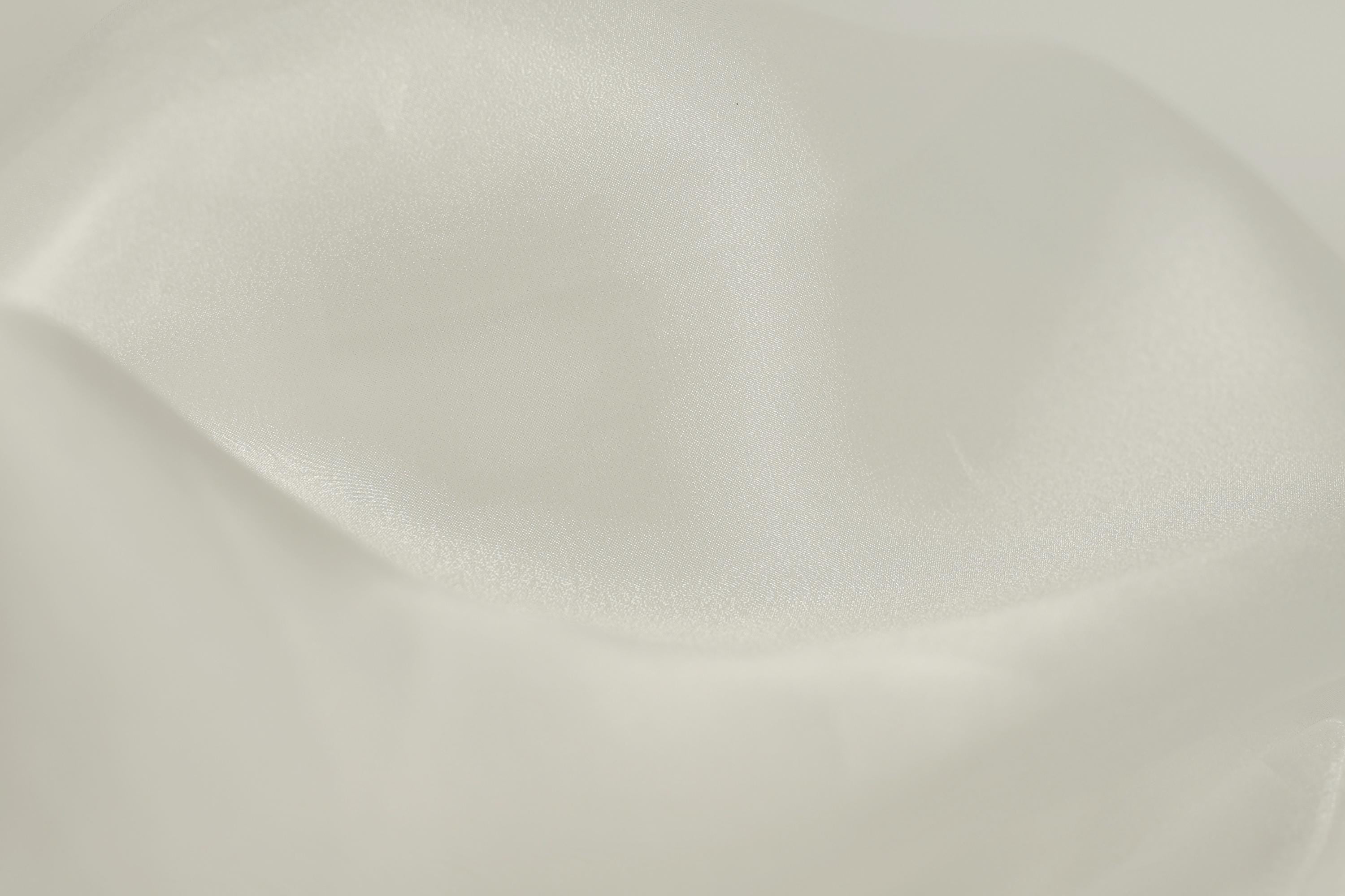 The image is a close-up of a white fabric, possibly silk or satin, with a smooth and shiny texture.