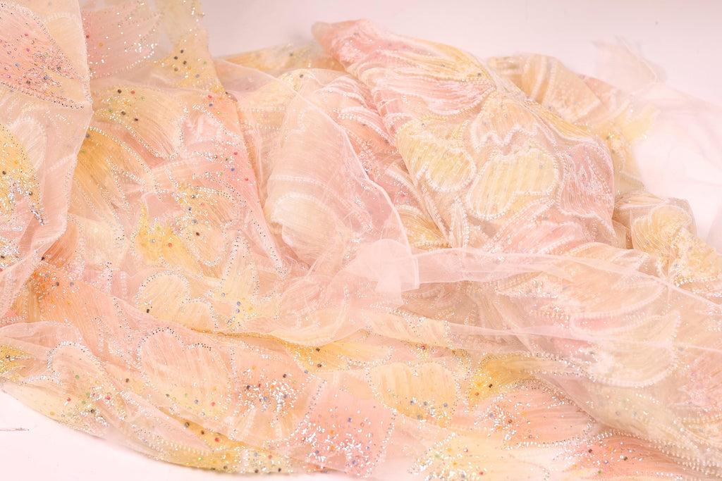 a close-up view of a delicate, sheer fabric with a floral pattern in shades of pink and yellow. The fabric appears to be made of sheer material, giving it a soft and delicate appearance.