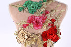 a close-up view of a mannequin torso adorned with a variety of colorful floral embroidery. The embroidery includes red, pink, and green flowers, as well as leaves and branches, creating a vibrant and eye-catching display.