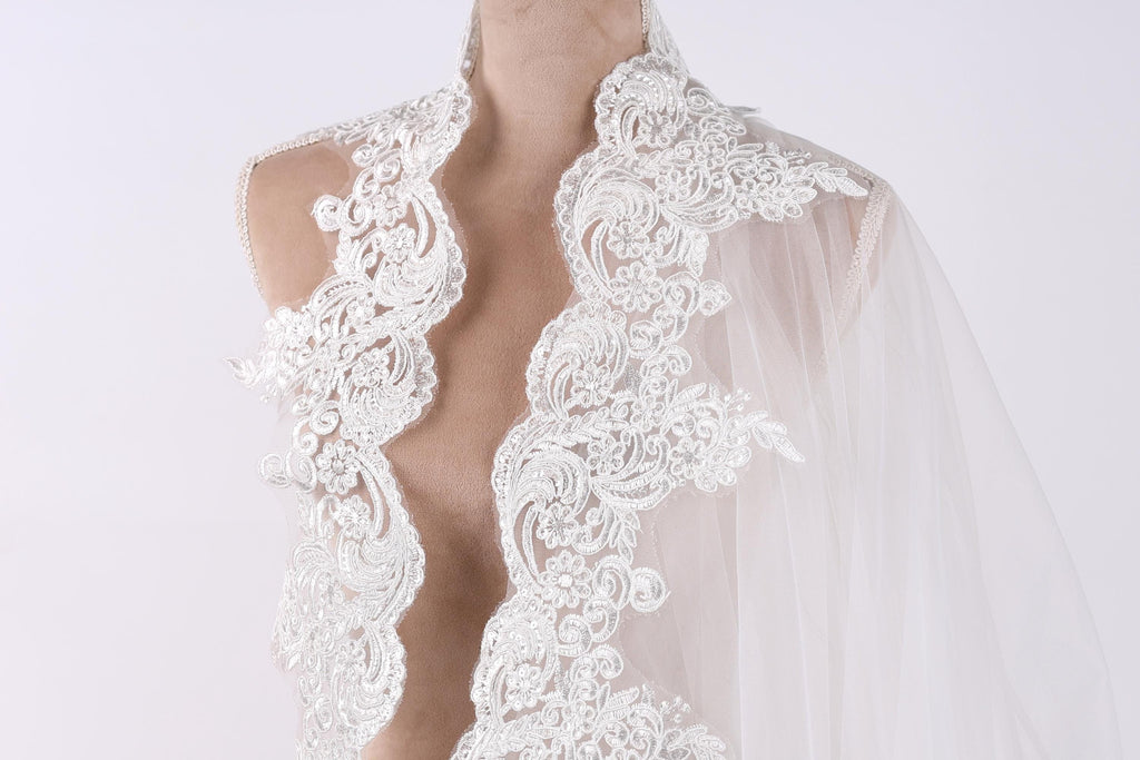 A mannequin wearing a white lace dress with intricate floral embroidery.