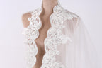 A mannequin wearing a white lace dress with intricate floral embroidery.