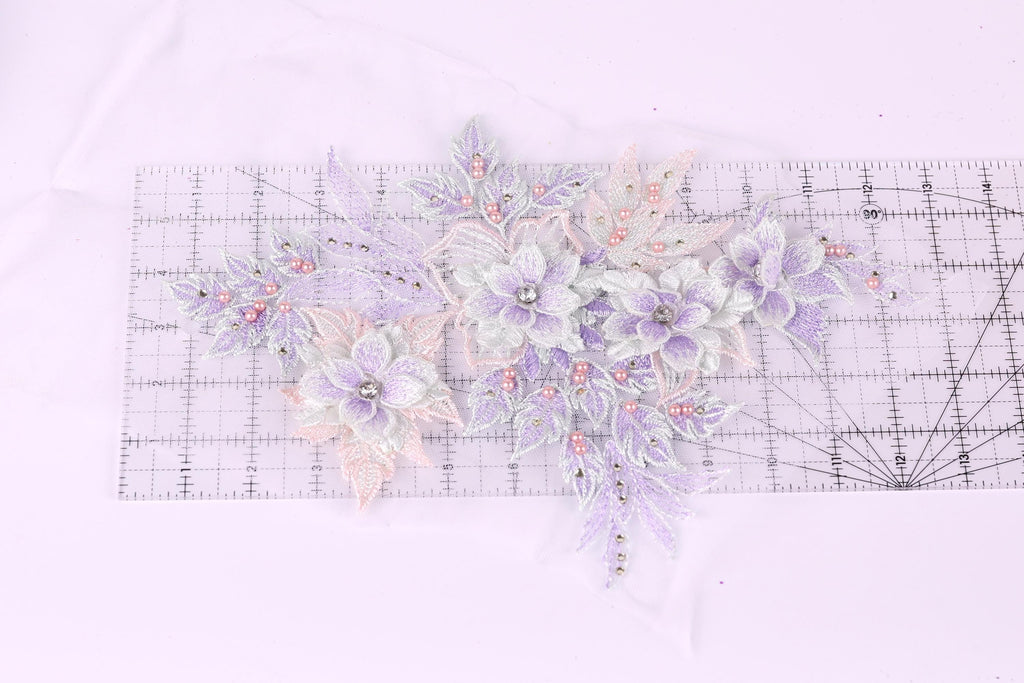 a collection of delicate, pastel-colored flowers and leaves, with some embellished with small beads, arranged on a transparent surface.