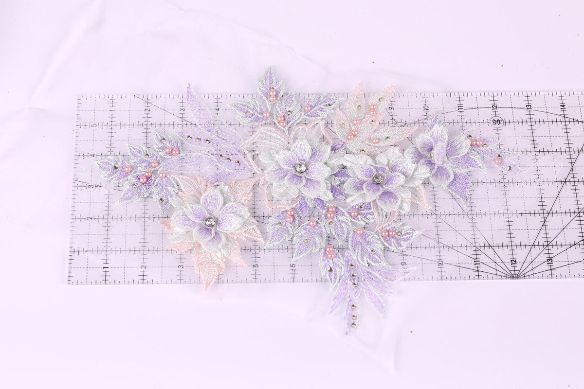 a collection of delicate, pastel-colored flowers and leaves, with some embellished with small beads, arranged on a transparent surface.