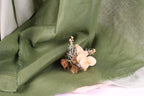 A close-up view of a green fabric with a small bouquet of dried flowers resting on it.