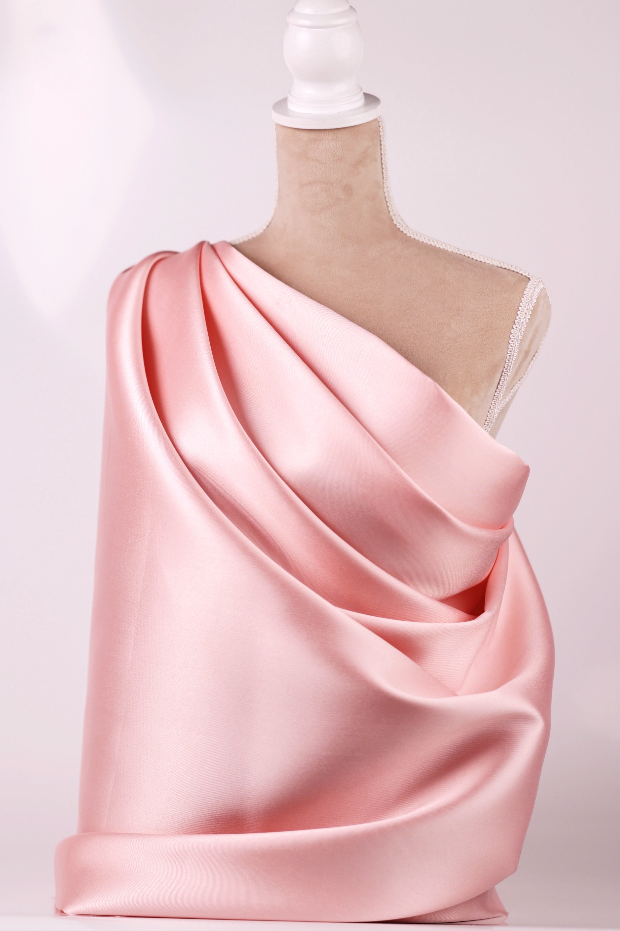 A mannequin wearing a pink satin draped over its body.