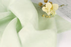 a close-up view of a delicate flower resting on a soft, light green fabric.
