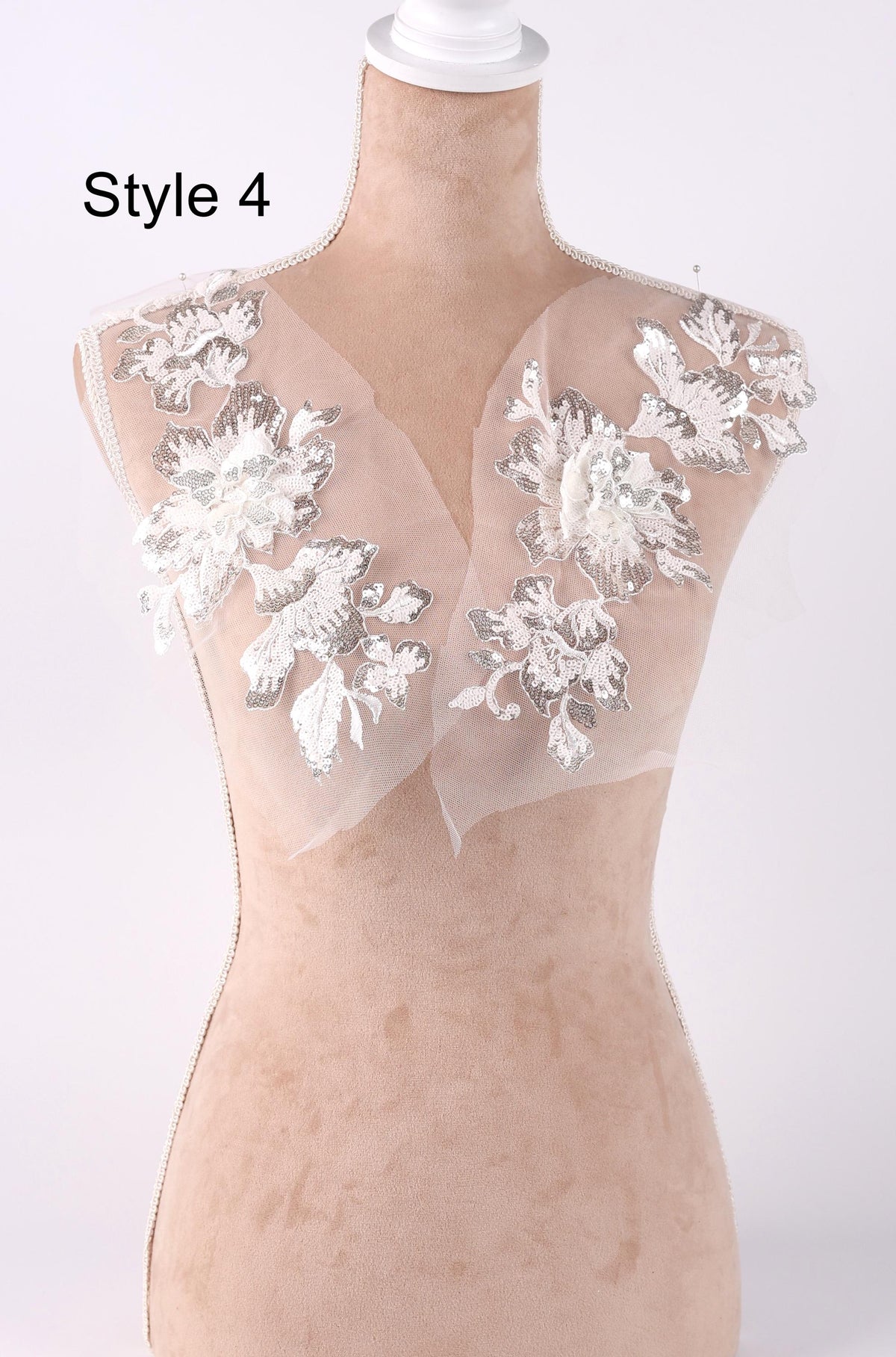 A mannequin with a white lace bodice and floral embellishments on the shoulders.