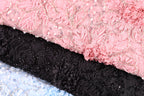 a close-up view of a fabric with a pink floral pattern and black lace-like texture.