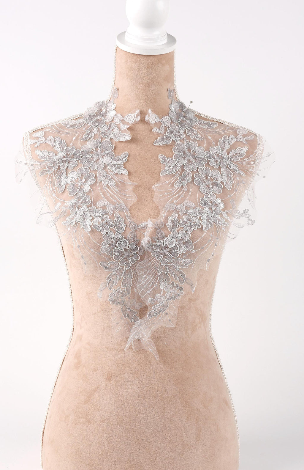 A mannequin wearing a white lace dress with intricate floral embroidery.