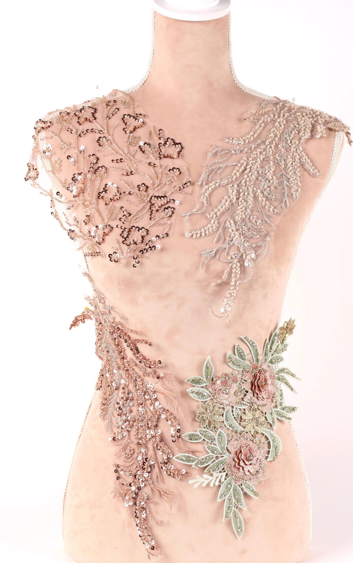 A mannequin wearing a dress with intricate beaded and embroidered details, including floral and leaf patterns.