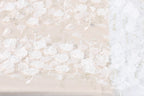 The image is a close-up of a fabric with a floral pattern, featuring numerous white flowers and delicate details.