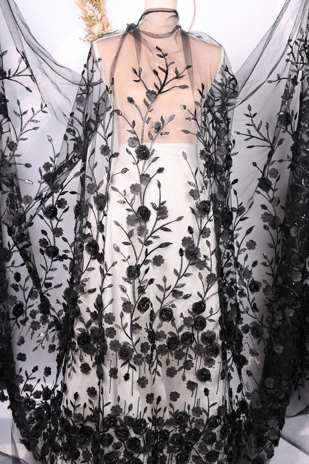 a dress with a black and white floral pattern, including black roses and leaves. The dress appears to be a long, flowing garment with a sheer overlay.
