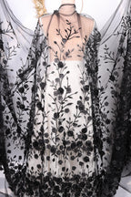 a dress with a black and white floral pattern, including black roses and leaves. The dress appears to be a long, flowing garment with a sheer overlay.