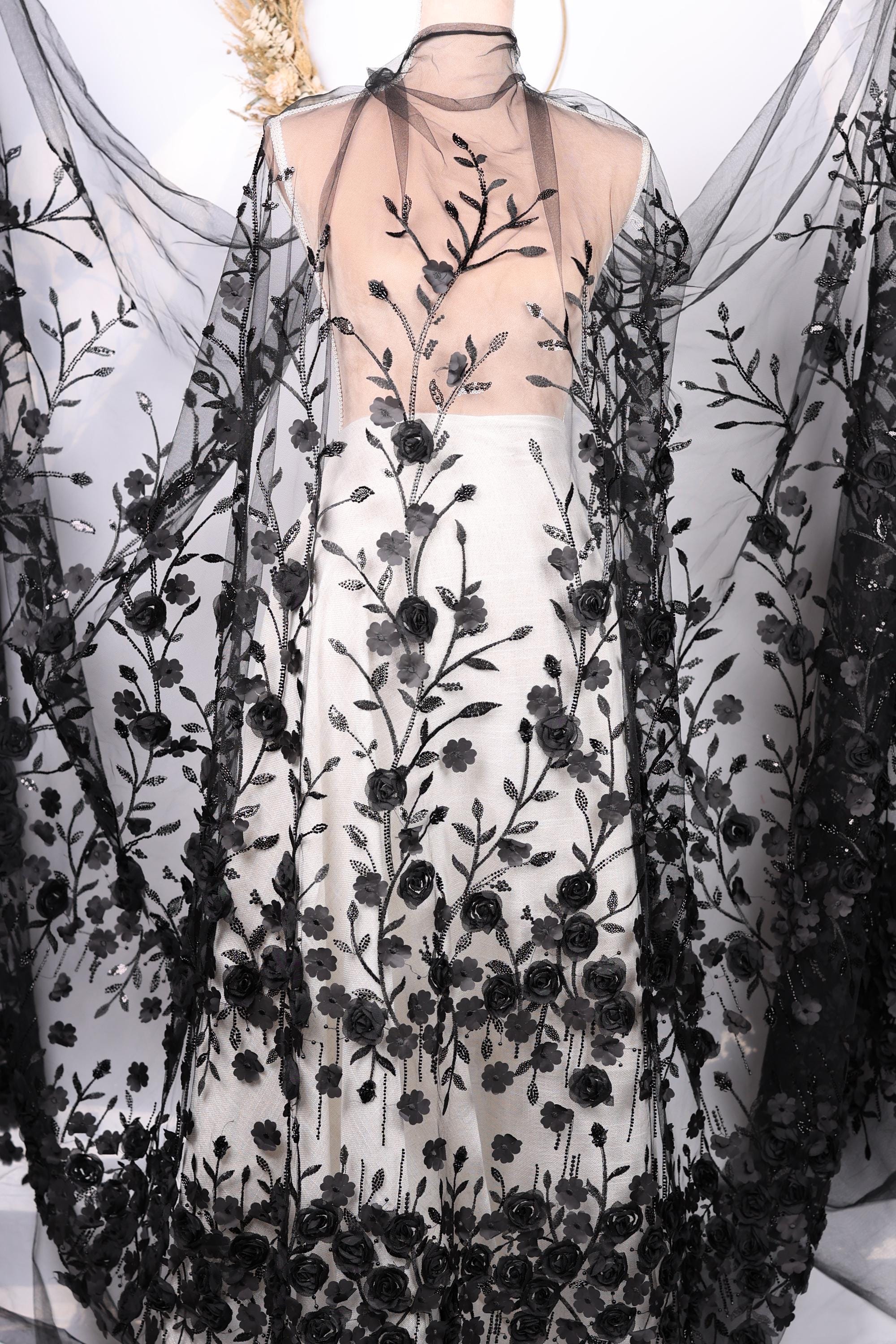 a dress with a black and white floral pattern, including black roses and leaves. The dress appears to be a long, flowing garment with a sheer overlay.