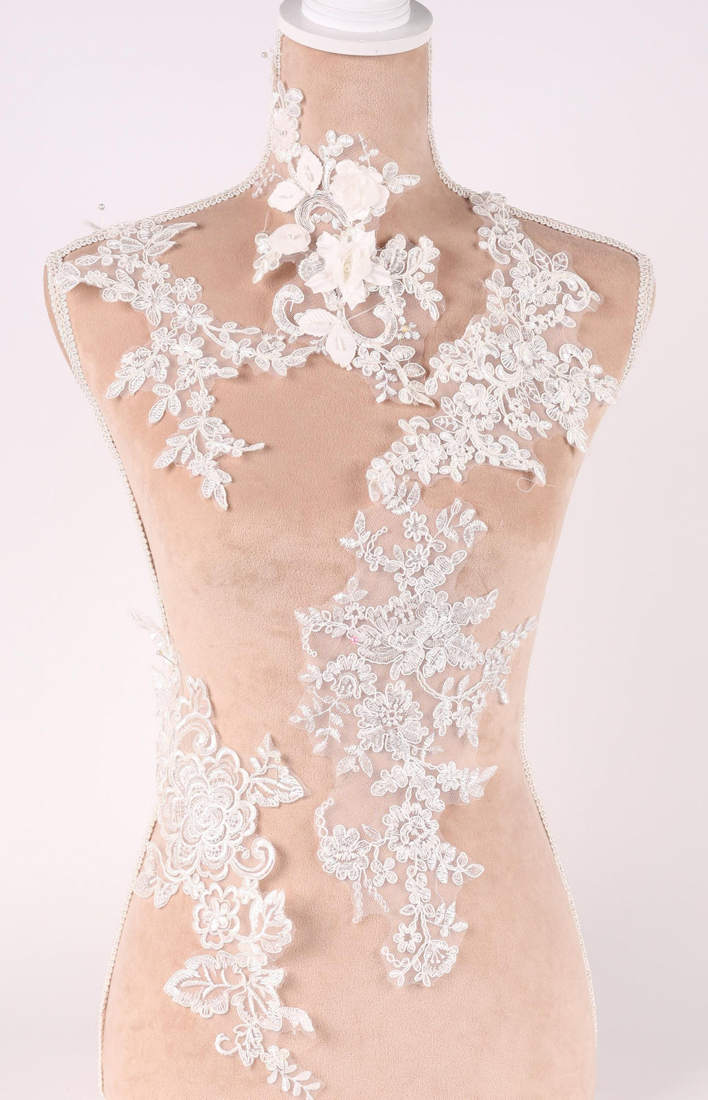 A mannequin wearing a dress with intricate white lace and floral embroidery details.