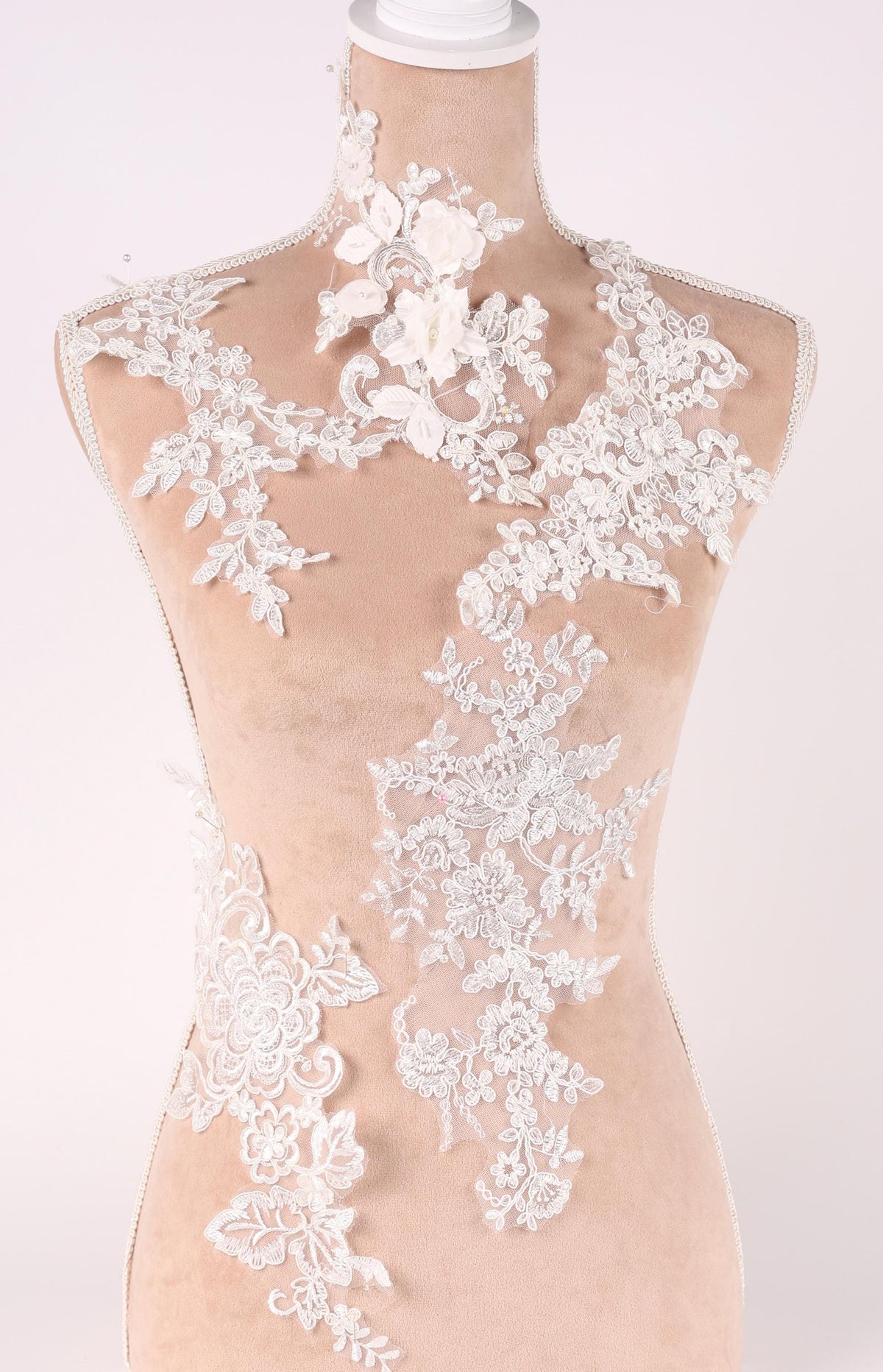 A mannequin wearing a dress with intricate white lace and floral embroidery details.