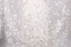 a close-up view of a delicate, white lace dress with intricate floral embroidery.