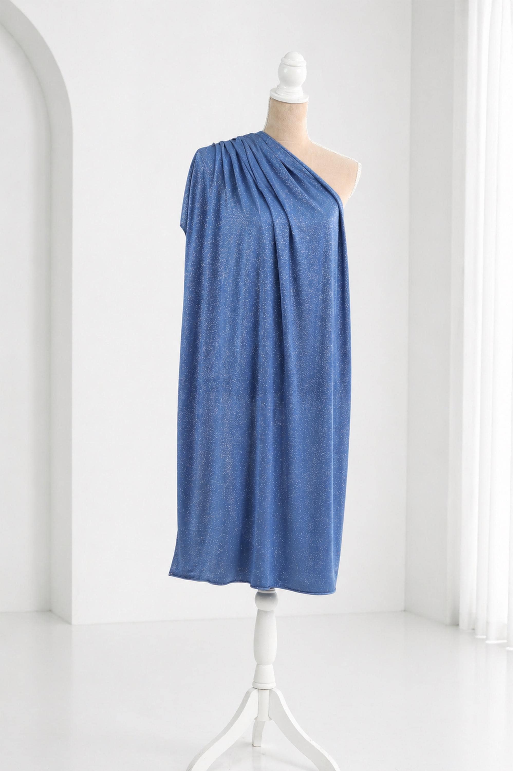 A blue one-shoulder dress displayed on a mannequin in a white room.