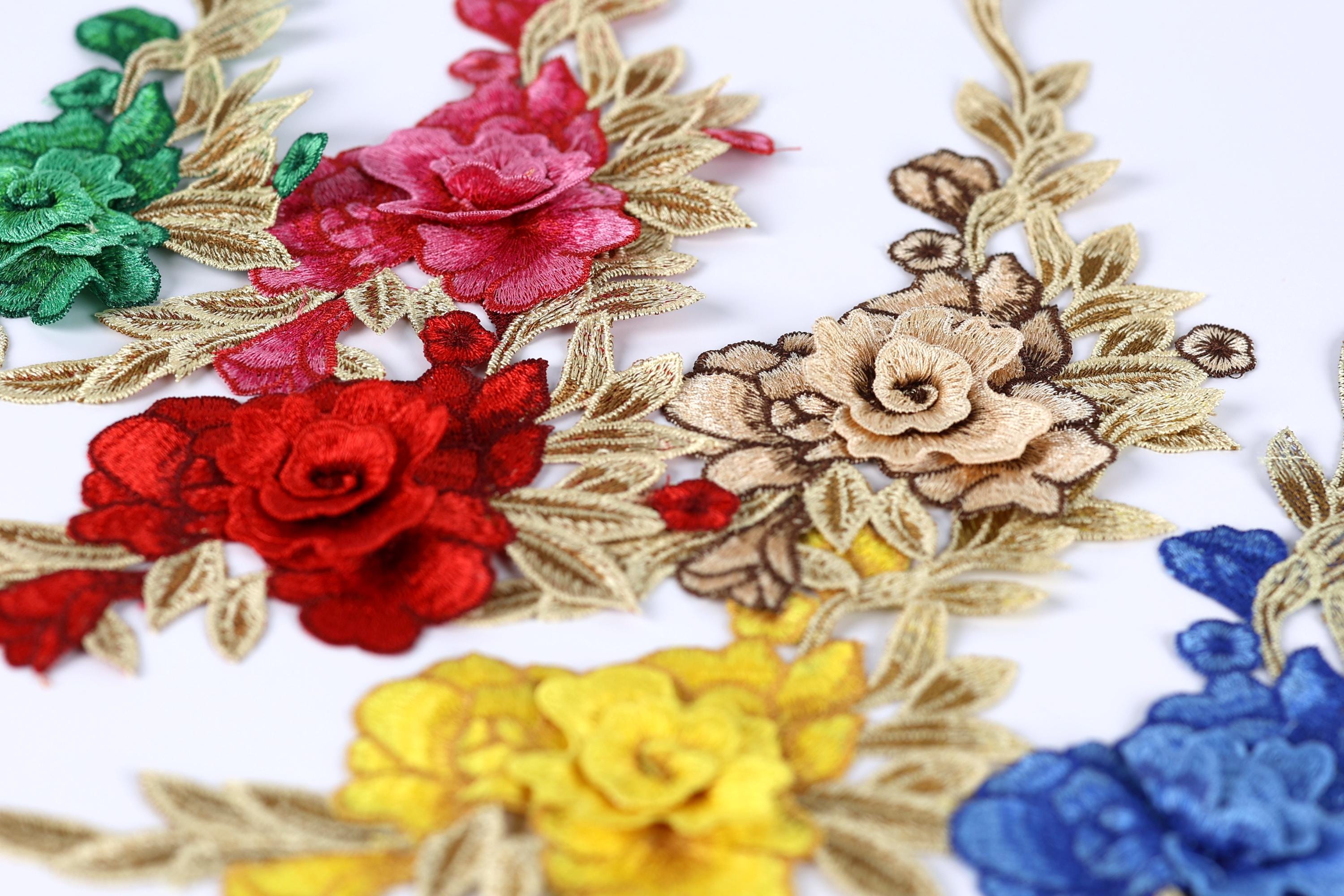 a close-up view of various colorful flower embroidery pieces, including red, pink, yellow, and blue flowers, arranged on a white background.