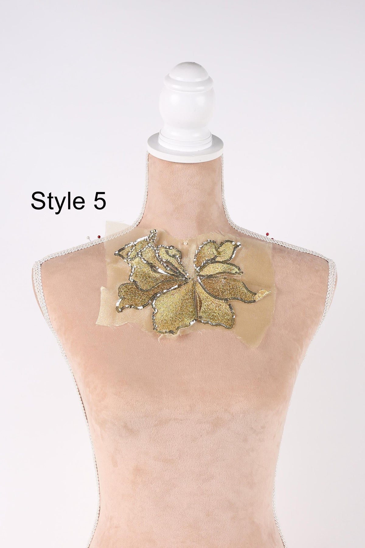 A mannequin with a gold sequin flower design on its neck.