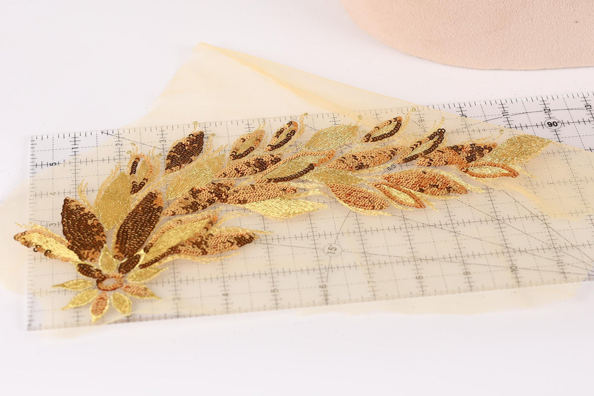a decorative piece with gold and brown leaf-like patterns, placed on a transparent surface.