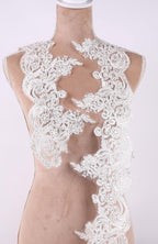 A mannequin wearing a white lace dress with intricate floral patterns.