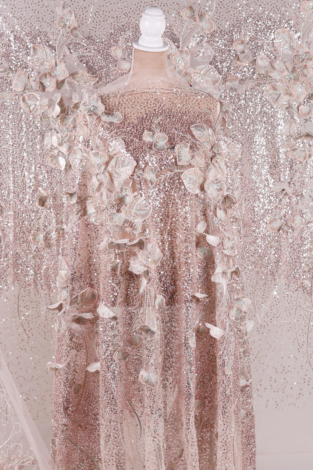 A pink sequined dress with delicate floral patterns, displayed on a mannequin.