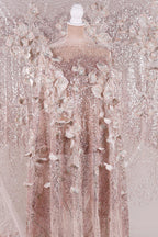 A pink sequined dress with delicate floral patterns, displayed on a mannequin.