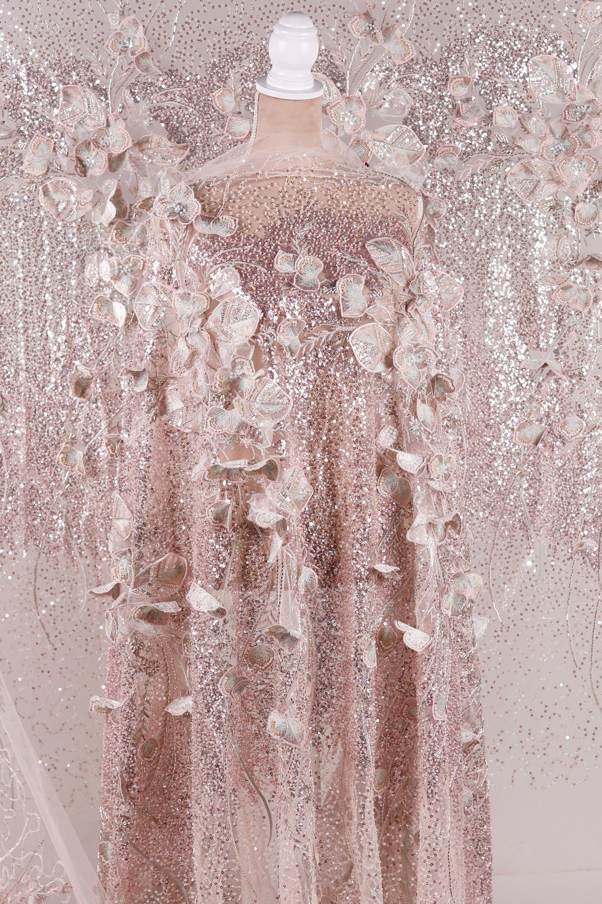 A pink sequined dress with delicate floral patterns, displayed on a mannequin.