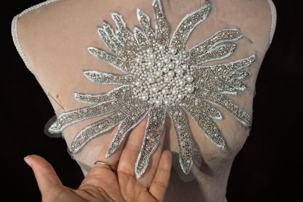 a woman's hand holding onto a dress with a flower on it