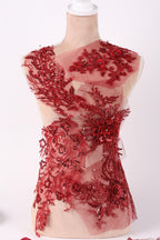 a red dress with intricate embroidery and embellishments, including a floral pattern and sequins.