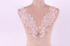A mannequin wearing a pink lace dress with intricate floral patterns on the shoulders and neckline.