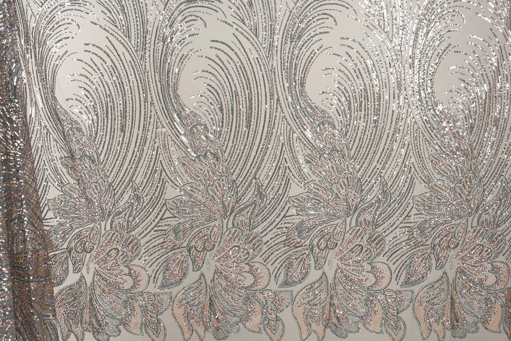 a close-up view of a fabric with a repeating pattern of silver and pink sequin designs. The pattern consists of various shapes and sizes of sequins arranged in a decorative manner, creating a visually striking and intricate design.