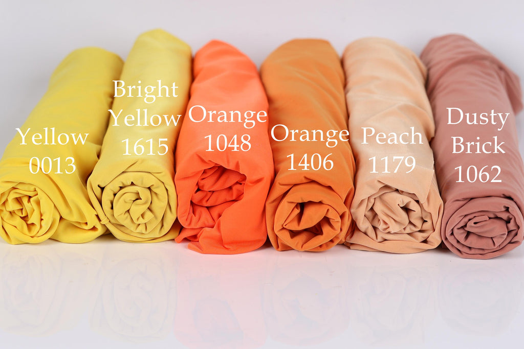 six rolled-up fabric swatches in different colors, including bright yellow, orange, peach, dusty brick, and peach.