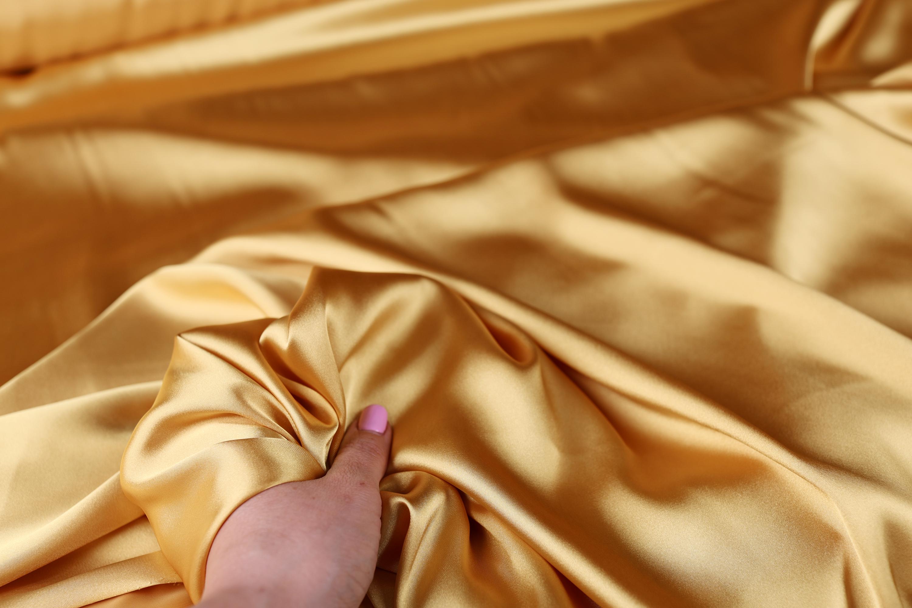 a person&#39;s hand on a satin material