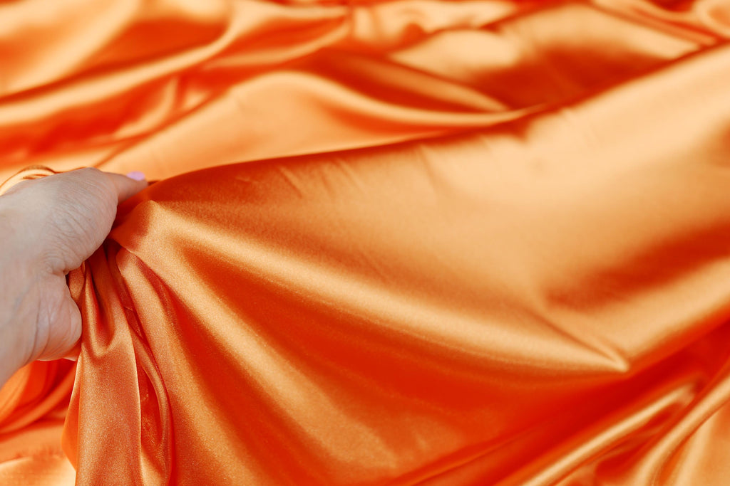 a person holding a piece of orange fabric