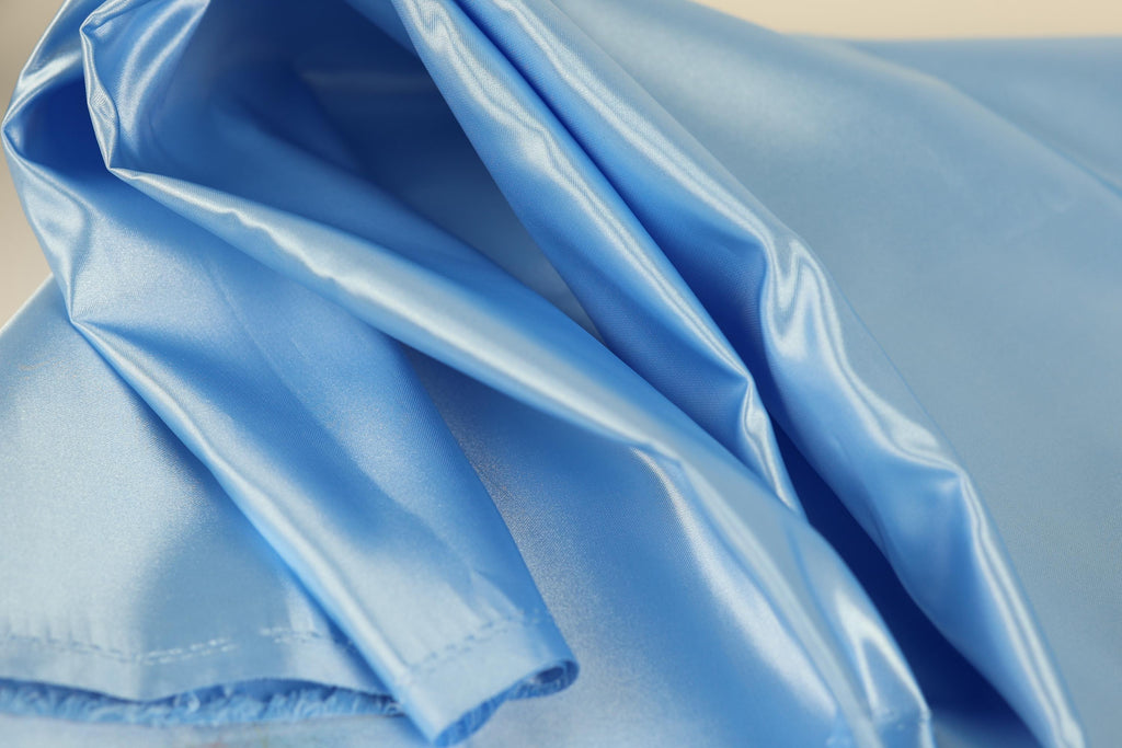 a close-up view of a blue satin fabric, with its folds and creases visible.