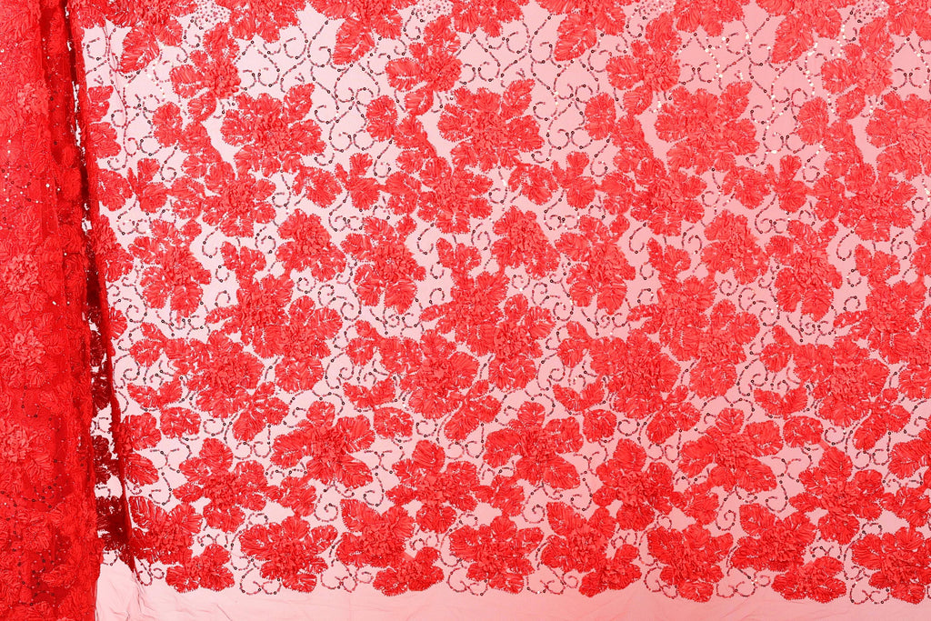 a close-up view of a red fabric with a floral pattern. The fabric appears to be made of a sheer material, with a repeating pattern of red flowers or leaves. The image does not contain any text or other discernible objects, and the focus is solely on the floral pattern on the fabric.