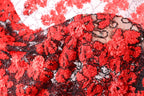 The image is a close-up of a fabric with a red and black floral pattern, featuring numerous small red flowers and black beads or sequins.